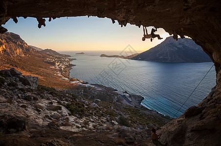 男性攀岩者在山洞的屋顶上攀爬悬崖成人运动天空风景男人登山者高度日落洞穴图片