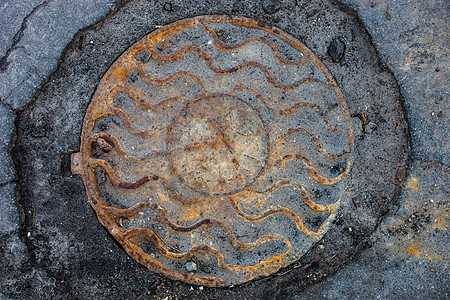 在破碎沥青表面有生锈金属覆盖的坑洞路面风化盘子圆圈电缆空间裂缝地面城市孵化图片