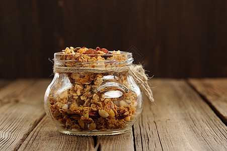Granola装在罐子中 用木制背面和石膏包装双色的木制背景木质种子食物早餐水果酒吧缠绕木桌盘子坚果图片