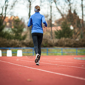 年轻妇女在赛场和田径体育场跑步天空女孩微笑女性竞赛娱乐女士竞技运动蓝色图片