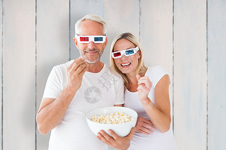 幸福的情侣穿着3D眼镜吃爆米花的综合画面地板微笑金发女郎夫妻感情男性休闲地面女士击剑图片