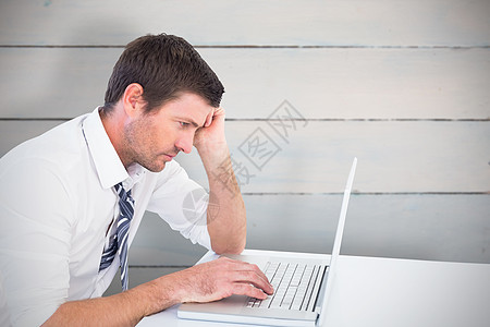 专注的商务人士在他的笔记本电脑上工作的复合图像地面蓝色木板桌子木头男人白色人士男性商业图片