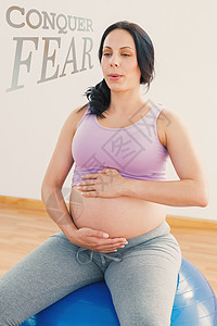 怀孕褐发孕妇坐在锻炼球呼吸的复合图象腹部护理闲暇竞技身体运动孕妇装健身运动服瑜伽图片