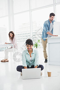 使用笔记本电脑坐在地板上工作的快乐女商务人士人士女性潮人商务桌子办公室混血地面咖啡屏幕图片