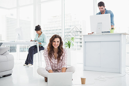 使用笔记本电脑坐在地板上工作的快乐女商务人士咖啡休闲女性女士商务屏幕混血桌子热饮微笑图片