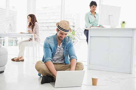 坐在地板上使用笔记本电脑的快乐商务人士休闲屏幕外带咖啡热饮工作工作室女性办公室地面图片