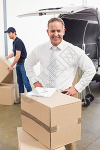微笑经理站在堆叠的纸板箱后面套装送货员人士送货工作双手接收商业男人码头图片