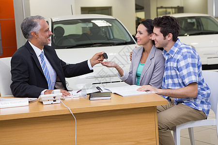 推销员给一对夫妇车钥匙销售交易购物协议桌子快乐运输代理商零售汽车图片