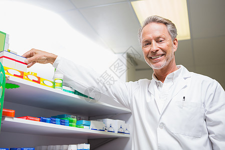 高级药剂师从货架上取药制药处方男性药品医院药剂工作架医疗贮存微笑图片