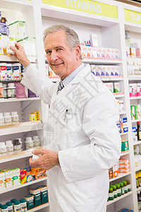 药剂师从货架上取药药店制药快乐微笑处方男人药品阅读实验盒子图片
