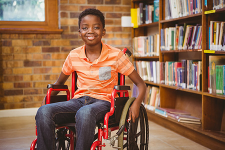 坐在图书馆轮椅上男孩的肖像图书知识架子学习小学砖墙文学病人功能书架图片