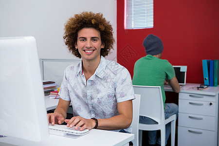在办公室使用计算机的临时性商业经营人微笑技术键盘男性职场电脑显示器工作室头发电脑桌子图片