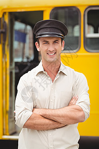 微笑的公共汽车司机看着相机双臂学校教育小学城市交通工具公车交通校车黄色图片