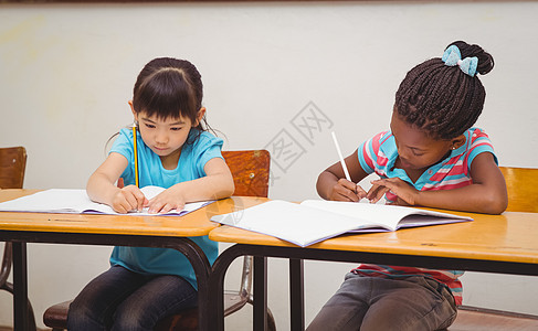 学生在书桌上写笔记本知识学习女孩童年班级瞳孔黑色教育记事本学校图片