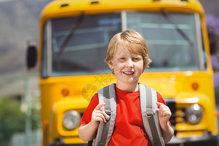 坐在校车旁边的可爱学生微笑着学校客车交通工具服务童年公共汽车知识男性瞳孔小学图片