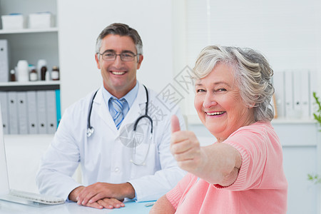 病人在与医生坐在一起时显示拇指抬头的标志图片