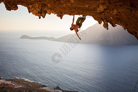 男性攀岩者在山洞的屋顶上攀爬高度天空活动太阳登山者成人岩石风景悬崖洞穴图片