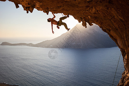 日落时在山洞的屋顶上攀岩男人男性天空挑战风景悬崖岩石运动高度太阳图片