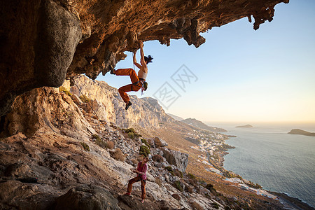 年轻妇女在洞穴中铅攀登登山者风景海岸天空活动悬崖岩石高度女士太阳图片