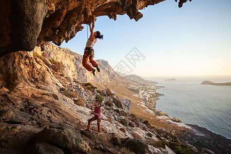年轻妇女在悬悬悬悬悬崖上登铅洞穴高度女士天空风景登山者女性绳索海岸太阳图片