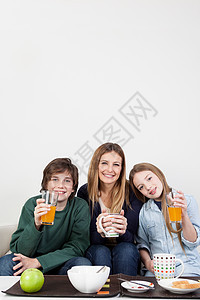 家人一起喝果汁快乐女孩们男孩们母亲橙子早餐儿子乐趣财产姐姐家庭图片