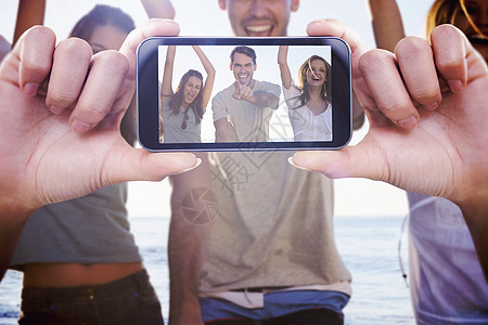 手持智能手机显示的复合图象假期快乐屏幕享受海洋自拍晴天朋友海滩女士图片