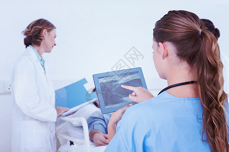 医生在平板电脑上看X光的复合图像检查药片团队男性女性诊所照顾血压男人病人图片