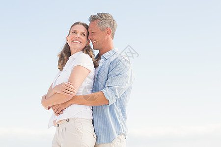 拥抱天空快乐的情侣互相微笑波浪海岸线男性拥抱休闲海洋自由晴天女性闲暇背景