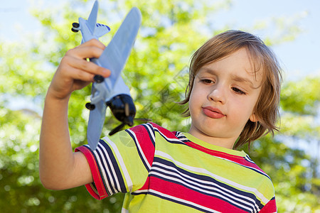 带着玩具飞机的快乐小男孩男性绿色童年农村公园绿地乐趣微笑阳光环境图片