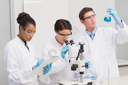 以显微镜和烧烤机认真工作的科学家研究技术工作服化学家生物学蓝色化学合作男性女性图片