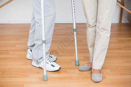 医生帮助她的病人用拐杖走路工具从业者身体骨科医疗职业医师男性制服药品图片