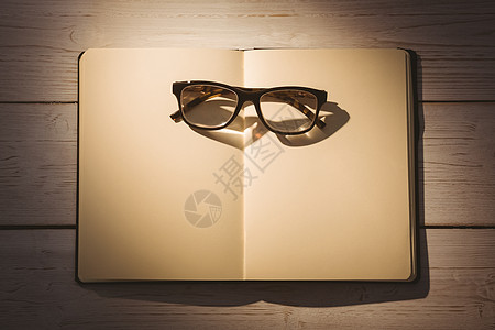 插画书带阅读眼镜的空白笔记纸教育商业页数阴影记事本木头桌子背景