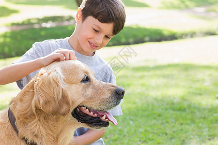 小男孩和他的狗在公园里短发头发家畜草地微笑草原绿地拥抱棕色男性图片