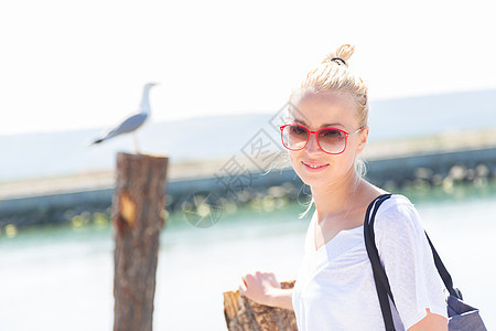 夏天在海滩上的女人金发女郎衬衫享受海岸魅力姿势海鸥快乐手提包码头图片