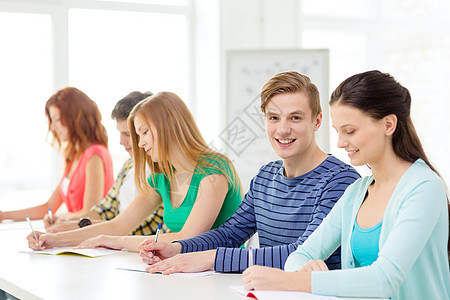 学校里带着课本 微笑着笑着的学生班级测试男性课堂同学团队男孩们演讲图书馆写作背景图片