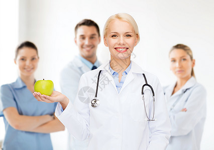 带着绿苹果 微笑着的女医生诊所团体长袍食物专家饮食咨询医疗保险职员女士图片