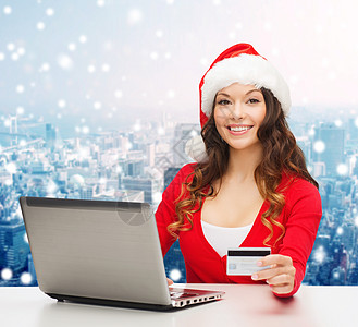 带着信用卡和笔记本电脑的微笑着的妇女销售信用城市摩天大楼帮手购物假期命令雪花开支图片