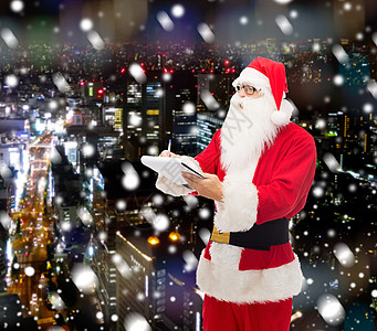 圣诞节狂欢穿着圣塔的装扮和笔记本的人戏服建筑物写作雪花摩天大楼胡须惊喜庆典假期笔记背景