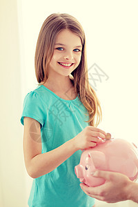 笑笑的小女孩把硬币放进小猪银行房间节俭小猪学生投资青春期女学生货币孩子女孩图片