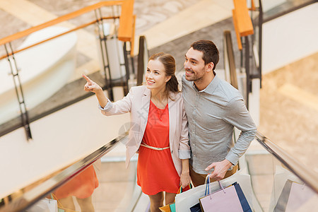 快乐的年轻夫妇和购物商场购物袋拉丁购物狂朋友们女朋友自动扶梯零售顾客男人购物中心微笑图片