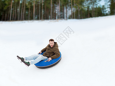快乐的年轻人滑下雪管季节男人管子乐趣雪胎活动闲暇男生男性骑术图片