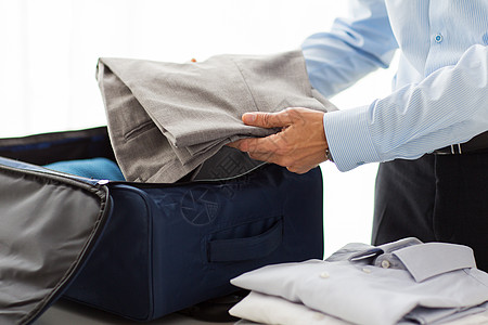 商务人士将衣服包装在旅行袋中折叠衬衫准备房间裤子旅行行李男性工作人士图片