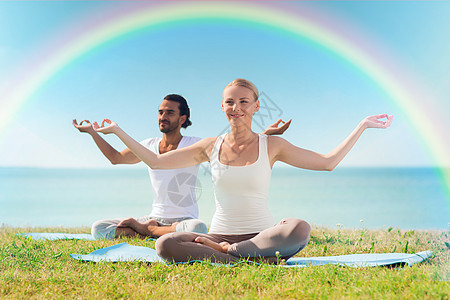 在户外做瑜伽锻炼的情侣微笑身体天空姿势彩虹活力火车女士脉轮运动装运动图片