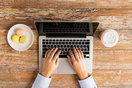 用笔记本电脑和咖啡搭紧女性手杯子键盘饮料教育学生饼干桌子人士互联网广告图片