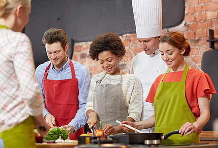 快乐的朋友和厨师在厨房做饭家庭女孩们转矩教学导师餐厅友谊夫妻蔬菜烹饪图片