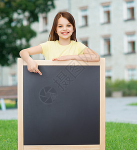 快乐的小女孩用手指对黑板木板学校广告教育课堂学生广告牌孩子校园学习图片