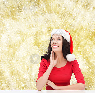 戴着圣诞老人帮手帽子的笑着女人庆典礼物假期快乐思维幸福女士桌子女孩图片