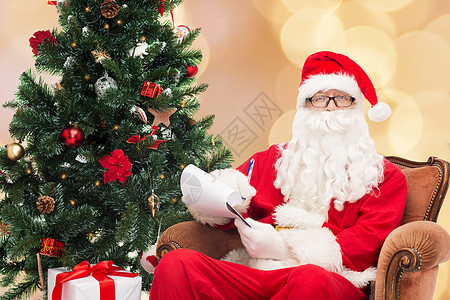 圣诞节狂欢穿着圣塔的装扮和笔记本的人惊喜扶手椅派对笔记假期庆典胡须眼镜戏服记事本背景