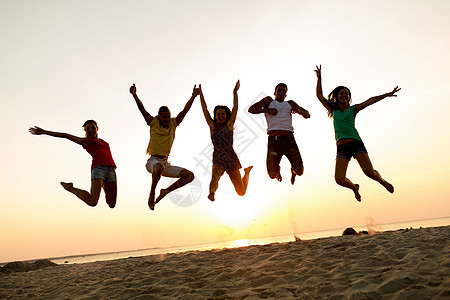 欢笑的朋友们在海滩上跳舞和跳跃日落女性团队家庭女孩们闲暇派对剪影假期幸福图片