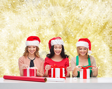 戴着圣诞老人帮手帽子的笑着女人 装满礼物惊喜装潢女性团体假期包装快乐朋友们幸福盒子图片